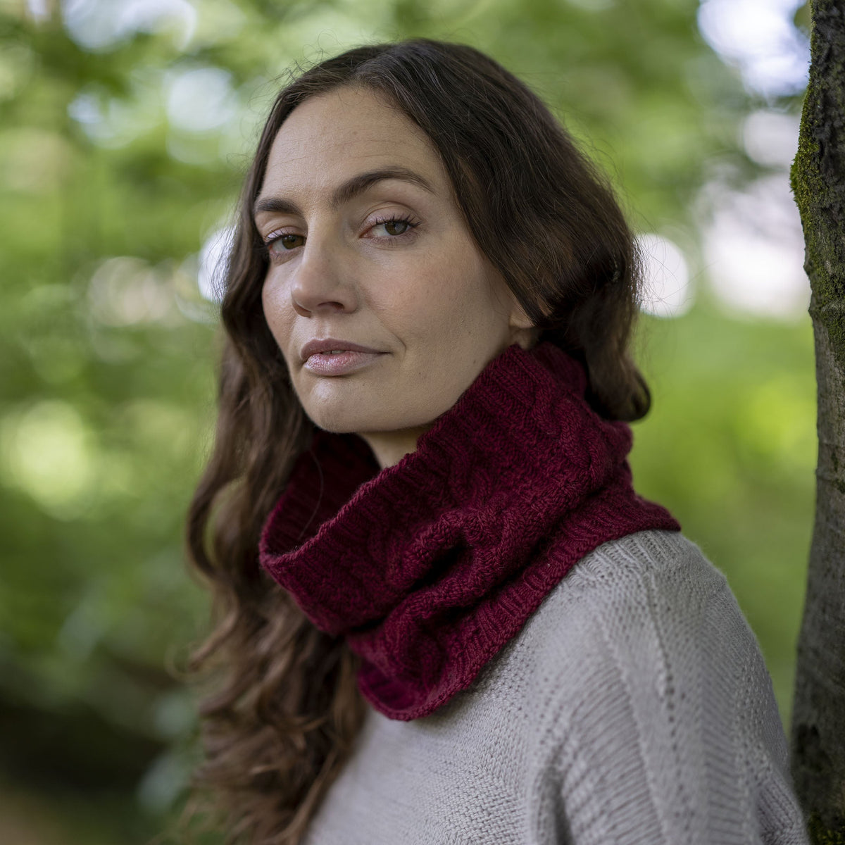 The Darvel Cabled Cowl in deep burgundy Orry Yarn Merino DK, worn at the neck, showing the cable and texture pattern.