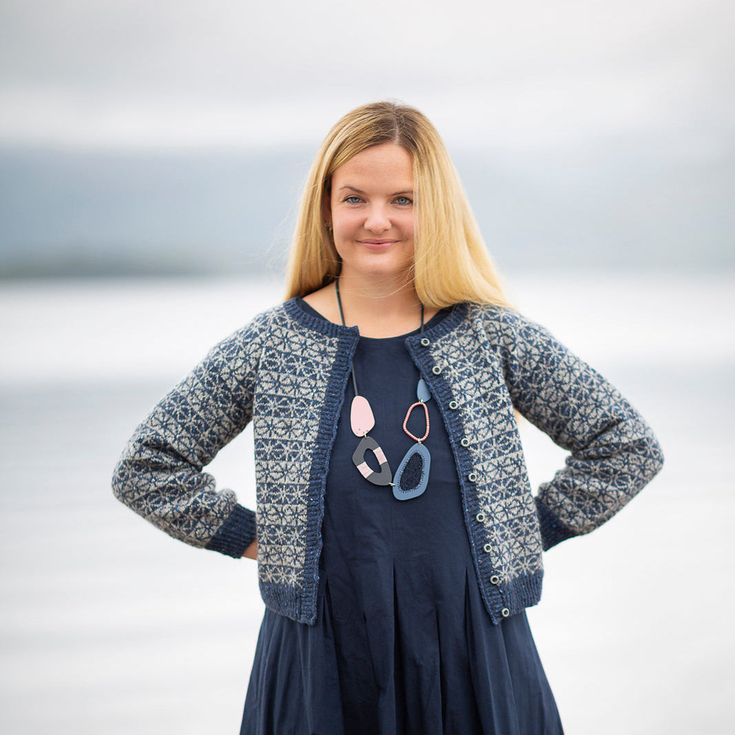 Tìoraidh colourwork cardigan worn open over a navy dress, showing the allover motif on body and sleeves