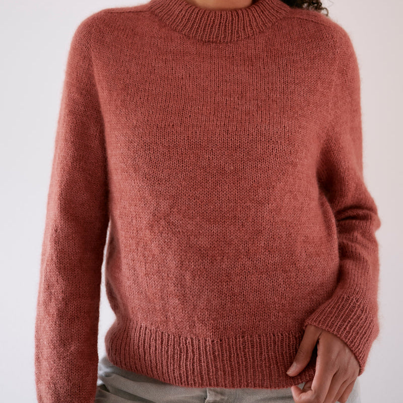 Person wearing a pink Knitting for Olive sweater against a white background