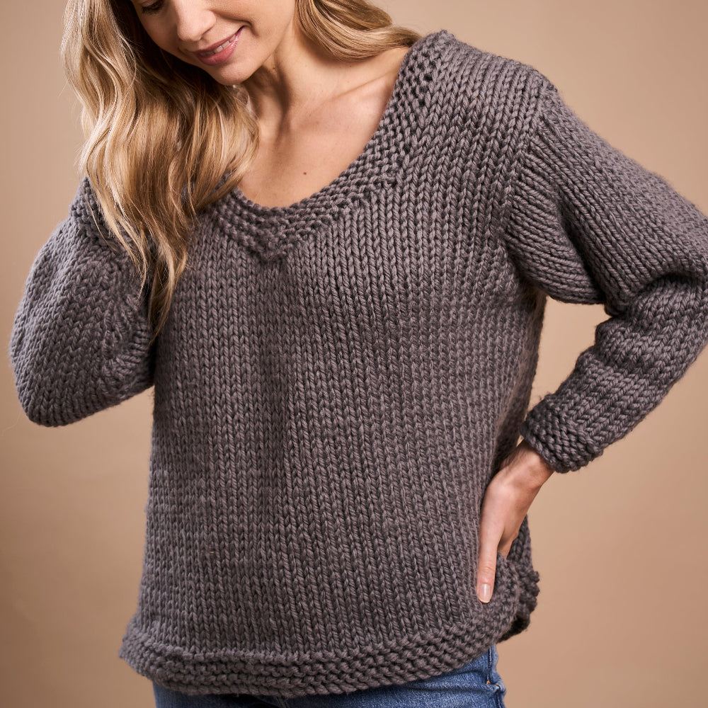 Woman wearing a chunky knit sweater against a beige background
