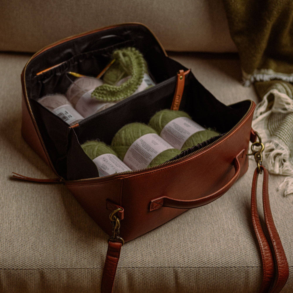 muud cleo midi brown leather knitting oand crochet project bag with green yarn and knitting needles on a beige couch